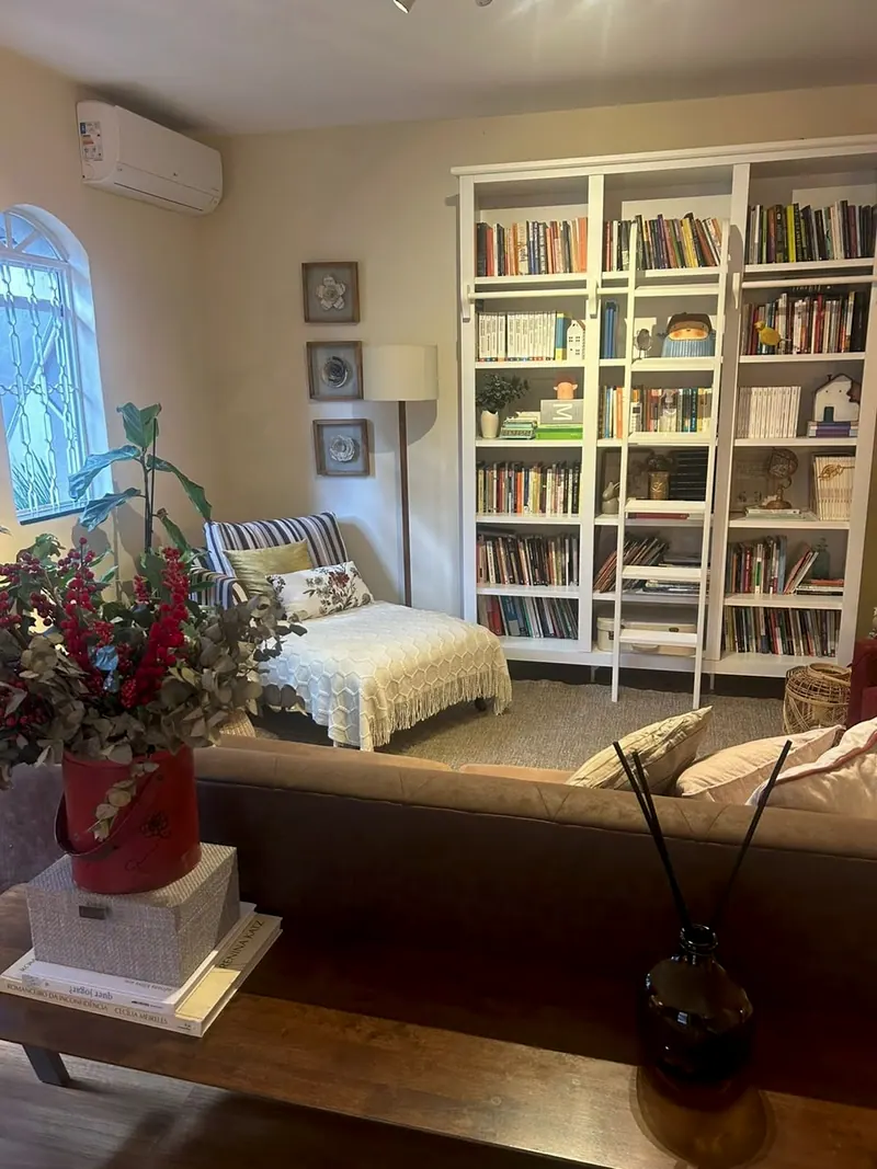 Recepção do consultório: sofá, divã e estante de livros branca